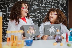 Two Girls in Lab Coats holding STEM Boxes